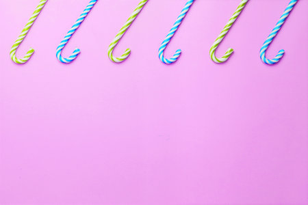 Five striped candy canes lined up on a pink background. Christmas, New Year, holiday. Flat lay minimalism holiday concept. Copy space.の写真素材