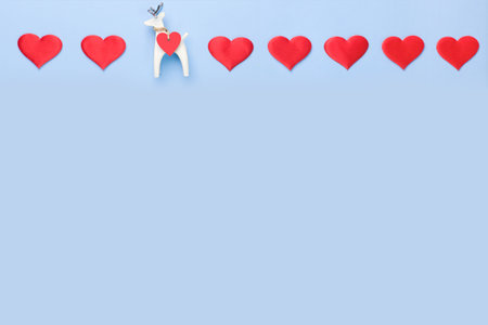 A row of hearts on a blue background with a small figure of a white deer. Valentines Day Concept . Copy space.の写真素材