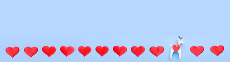 A row of hearts on a blue background with a small figure of a white deer. Valentines Day Concept . Banner.の写真素材