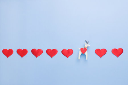 A row of hearts on a blue background with a small figure of a white deer. Valentines Day Concept . Copy space.の写真素材
