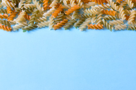 Uncooked three-colored italian pasta. Dried italian pasta on the blue surface. Colored natural pasta.の写真素材