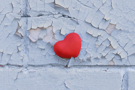 Red heart on an old cement wall with cracked grey paintの写真素材