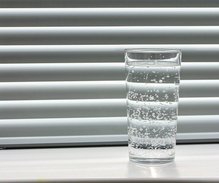 Glass of pure water on the windowsill, window with shuttersの写真素材