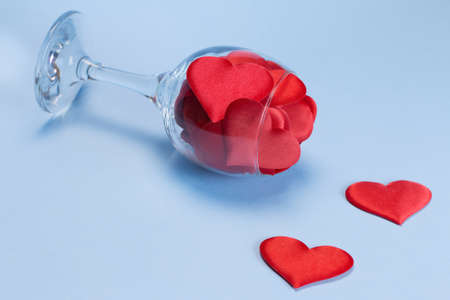 A glass full of satin red hearts on a blue background. Valentines day concept. Happy Valentines Day. Postcard. Copy space.の写真素材