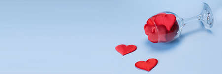 A glass full of satin red hearts on a blue background. Valentines day concept. Happy Valentines Day....