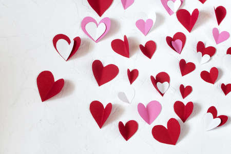 Red, white and pink paper hearts cut out of paper for decorating on Valentines Day on a white table. Valentines Day conceptの写真素材
