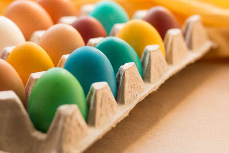 Yellow, red, orange, blue and green easter eggs painted with organic dyes in a cardboard tray on a table. Zero waste holiday. Traditional Easter. Easter concert.の写真素材