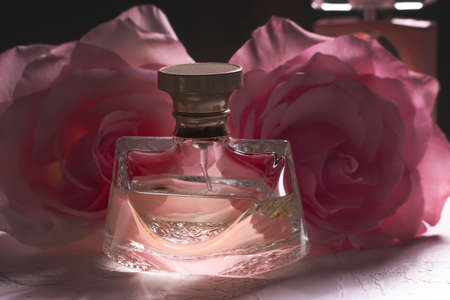 A bottle of perfume on the table with a pink rose. Perfumes, cosmetics, a collection of fragrances.の写真素材