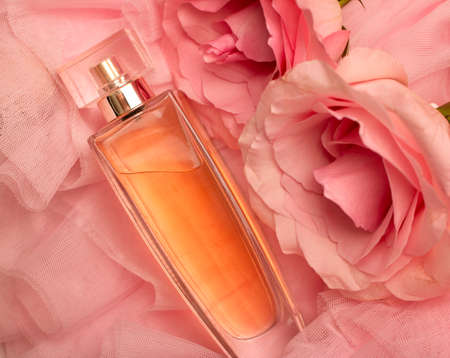 A bottle of perfume on pink veil with a pink rose. Perfumes, cosmetics, a collection of fragrances.の写真素材