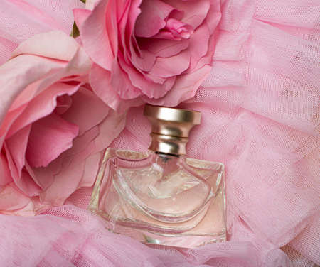 A bottle of perfume on pink veil with a pink rose. Perfumes, cosmetics, a collection of fragrances.の写真素材