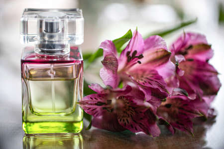 A bottle of perfume on the table with alstroemeria flowers. Perfumes, cosmetics, a collection of fragrances.の写真素材