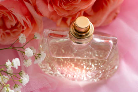 A bottle of perfume on pink veil with a pink rose. Perfumes, cosmetics, a collection of fragrances.の写真素材