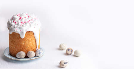 Traditional homemade Easter cake, decorated with glaze and pastry sprinkles on a blue plate on a white table with quail eggs. Happy Easter.の写真素材