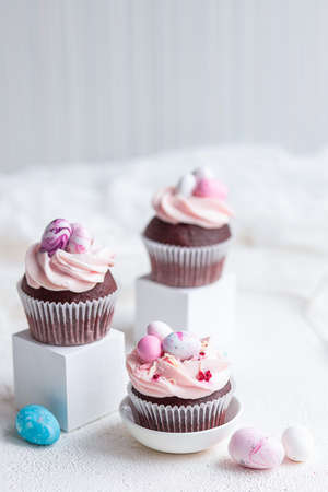 Three Easter chocolate cupcakes with caramel filling and decoration of small Easter eggs from marzipan on the white background. Selective focusの写真素材