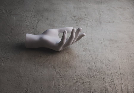Plastic hand on a grey concrete surface. Minimalism. Copy spaceの写真素材