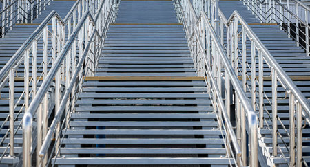A staircase with gray concrete steps and a metal railings leading up. An element of urban architectureの写真素材