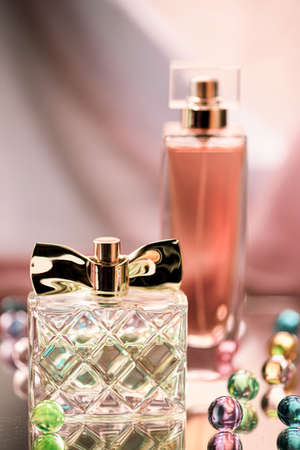 Two perfume bottles with glass colored balls on a glass surface. Perfumes, cosmetics, a collection of fragrances.の写真素材
