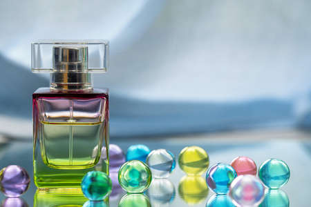 Perfume bottle with glass colored balls on a light background. Perfumes, cosmetics, a collection of fragrances.の写真素材