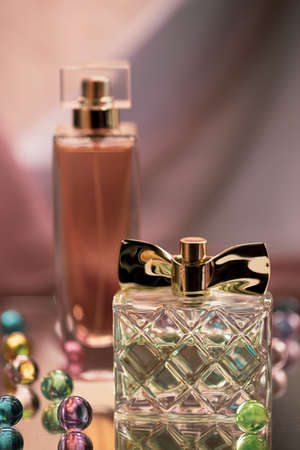 Two perfume bottles with glass colored balls on a glass surface. Perfumes, cosmetics, a collection of fragrances.の写真素材