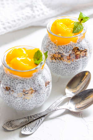Healthy Chia Pudding with Coconut Milk, mango, chia seeds, granola in a Glass. Concept of healthy eating, healthy lifestyle, dieting, fitness menu.の写真素材