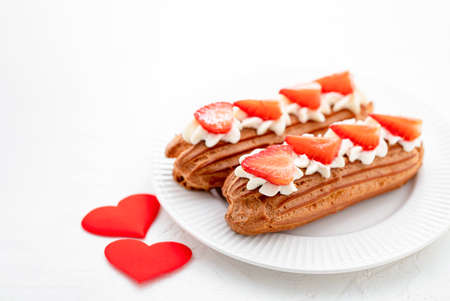 Eclairs with cream and strawberries on a white plate. Valentines Day Conceptの写真素材