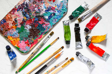 Oil paints and paint brushes with palette on white table.の写真素材