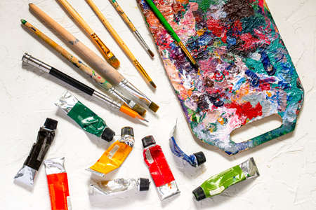Oil paints and paint brushes with palette on white table.の写真素材