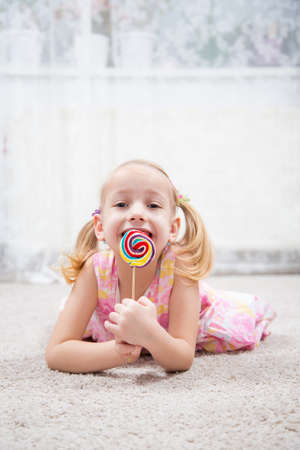Funny child with candy lollipop, happy little girl eating big sugar lollipopの写真素材