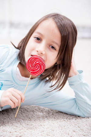 happy little girl eating sugar candyの写真素材