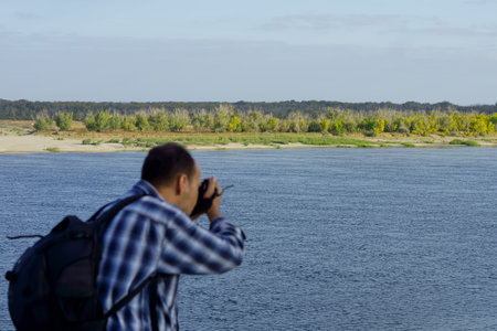 Photographer takes pictures of the landscape on the bank of the riverの写真素材