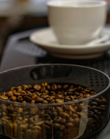 Coffee beans on a coffee grinder and a cup of coffee