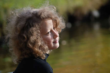 Pretty little girl sitting near a lakeの写真素材