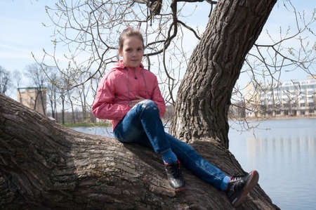 girl, sitting on a tree at the riverの写真素材