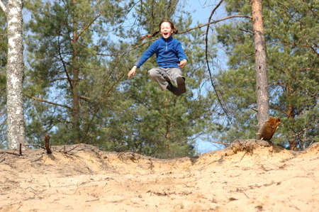 girl, jumping from a sandy slopeの写真素材