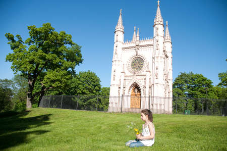Little girl with the bouquet of the field flowers on a background Gothic Choir in Petrodvorce, Saint Petersburg, Russiaの写真素材