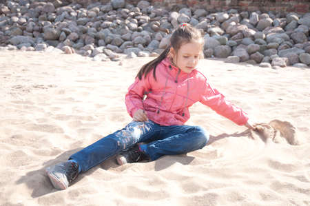 little girl, playing sand on a beachの写真素材