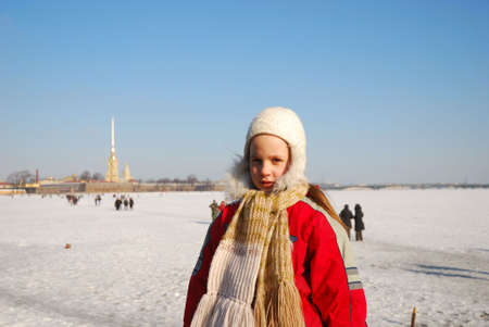 little girl in winter on a background the river Neva, covered by iceの写真素材