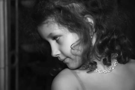 little girl with beautiful curlings hairs with a necklace on a neckの写真素材