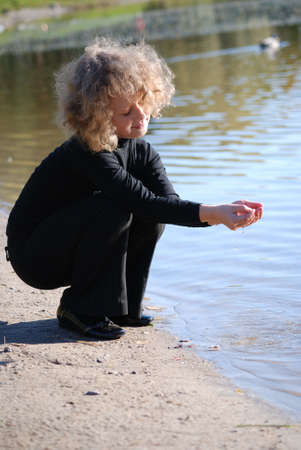 Pretty little girl sitting near a lakeの写真素材