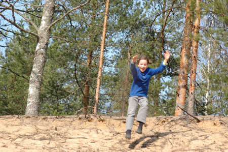 little girl, jumping from a sandy slopeの写真素材