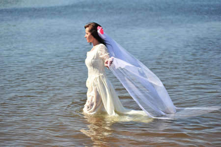 portrait of bride dressed in wedding gown in waterの写真素材