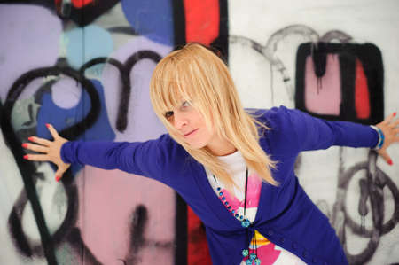 A beautiful young woman leaning against a wall covered in graffiti