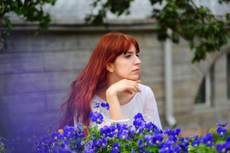 The red-haired girl near to blue a flowerの写真素材