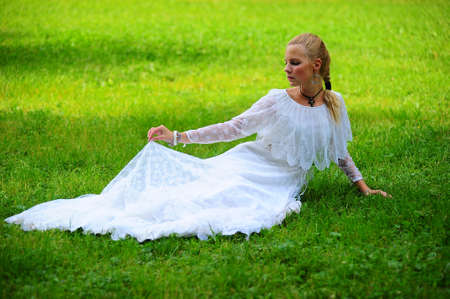The young girl in an ancient white dress on a grassの写真素材