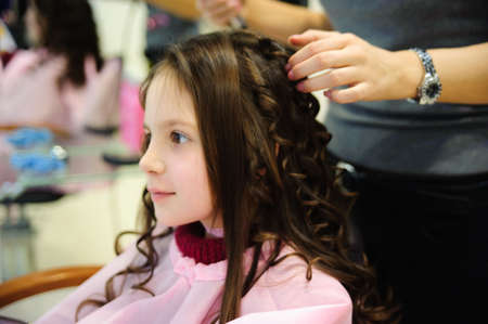 The little girl doing a hairdress in a hairdressing salonの写真素材