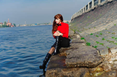 The girl sitting on quay at waterの写真素材