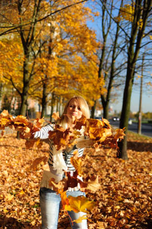 Portrait of a happy woman playing with autumn leaves 