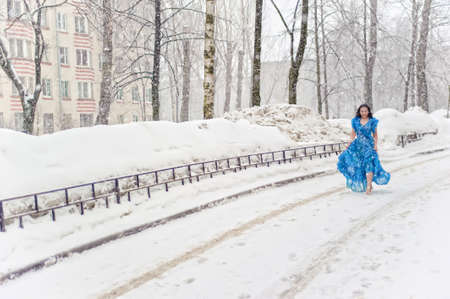 woman in a light dress running barefoot in the snowの写真素材