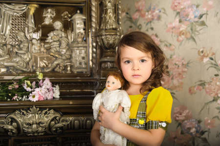 little girl with a doll in hands. photos in retro styleの写真素材