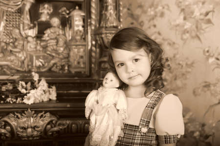 little girl with a doll in hands. photos in retro styleの写真素材